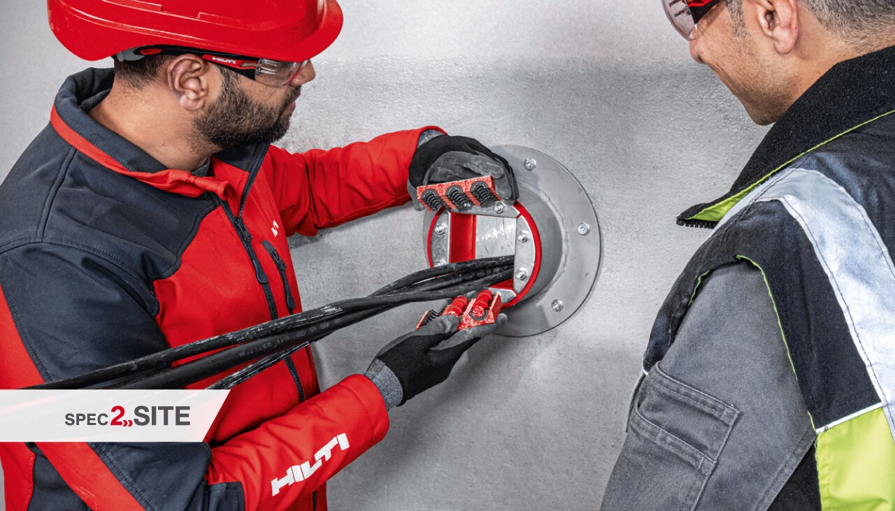 μηχανικός πεδίου της Hilti δείχνει σε πελάτη ένα χιτώνιο παθητικής πυροπροστασίας σε μια ηλεκτρολογική εγκατάσταση